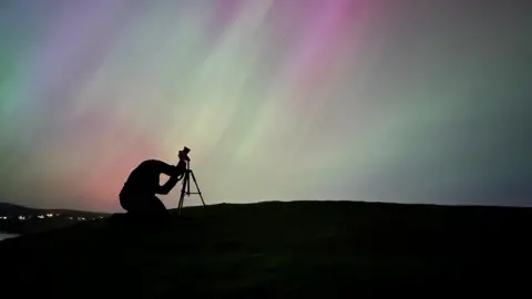 The silhouette of a photographer setting up his the northern lights