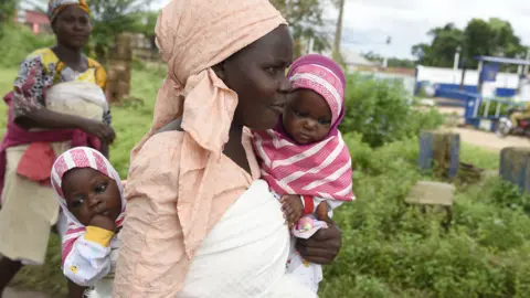 AFP A mother holds her baby twins in Igbo-Ora, Nigeria - 2019