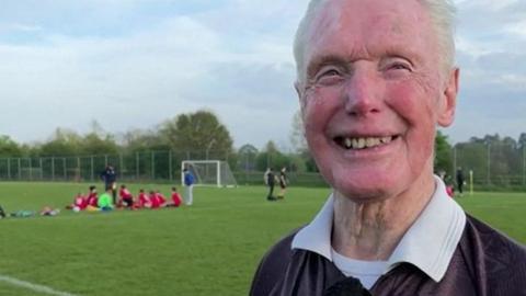 Bill Martin smiling with the football pitch in the background