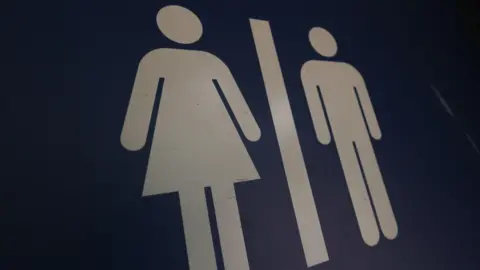 Shutterstock A blue gender neutral toilet sign, showing an image of a woman on the left and the image of a man on the right.