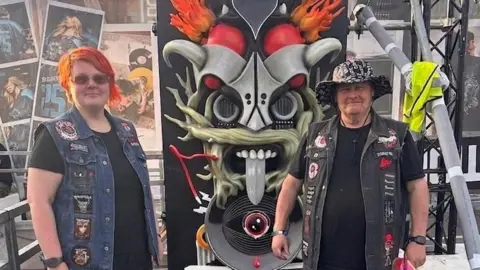Toni Rose Toni Rose and Danny Fox in denim battle jackets standing in front of a Download Festival sign