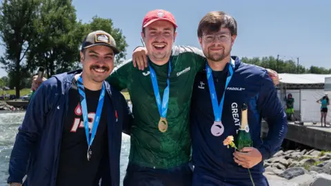 International Canoe Federation Eoghan Kelly, centre, wearing his gold medal with his arms around fellow medal winners