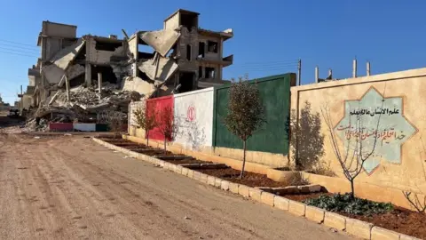 A dilapidated building on top of a dusty road 