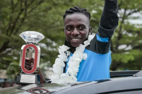 AFP Burundian athlete Francine Niyonsaba who set new world record of women's 2000m with 5 minutes 21 seconds and 56 hundredths of a second reacts to people from a car in Bujumbura, Burundi.