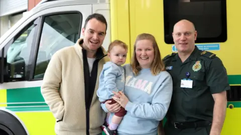 EEAST Tim, baby Cecilia, Alex and paramedic Mike Sage standing next to an ambulance