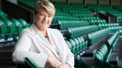 Woman in white suit in stadium with green chairs