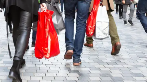 Getty Images People walking with shopping bags. Shot of people's legs. 