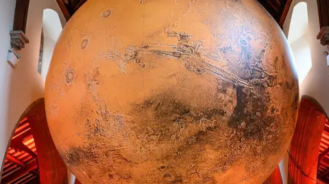 MANX SCENES A close-up the sculpture, which has an orange colour. The arches of the cathedral can be seen behind