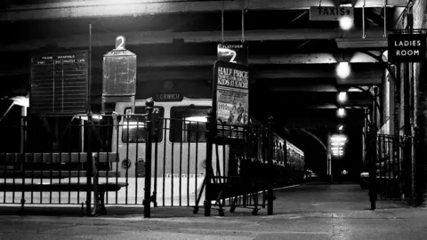 David Pearce A black and white image of the Lowestoft railway station from decades ago. A train with a sign on the front reading Ipswich rests at a platform. 