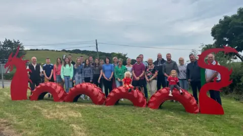 a red dragon sculpture with people standing behind