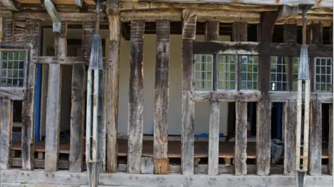 A close-up showing exposed timber frames of a Grade I listed building