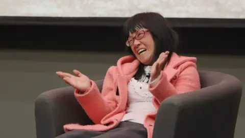 Getty Images Poet Yu Xiuhua leaning back in a chair and laughing