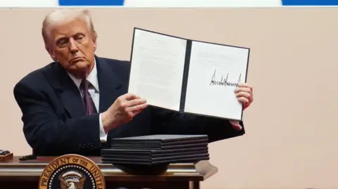 Getty Images Donald Trump signs executive orders on Monday after being sworn in as president for a second term.