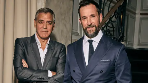 Getty Images George Clooney and Noah Wyle - both in suits looking at the camera.