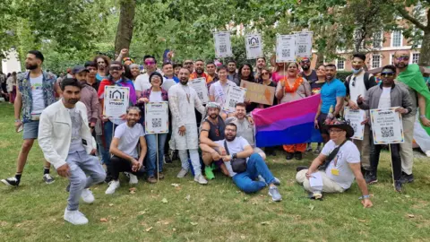 LGBTQI+ Faith A group of LGBTQI+ Faith members gathered on a grassy area, holding placards and flags at Pride in London last year.