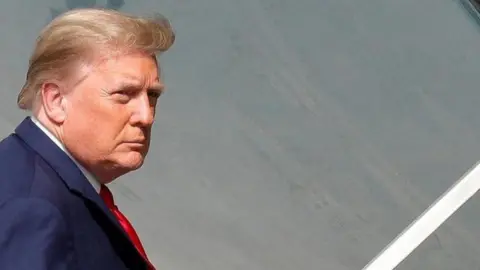 U.S. President Donald Trump is seen reflected while boarding Air Force One at Palm Beach International Airport in West Palm Beach, Florida, U.S., December 31, 2020
