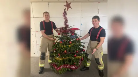 Guernsey Fire and Rescue Service Two fire fighters with a Christmas tree