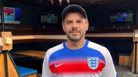 A man wearing a red, white and blue England football shirt