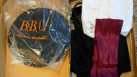 PA Media A costume box containing black, red and white clothing. Inside there is also a plastic bag with 'BBC television wardrobe' written in orange print. 