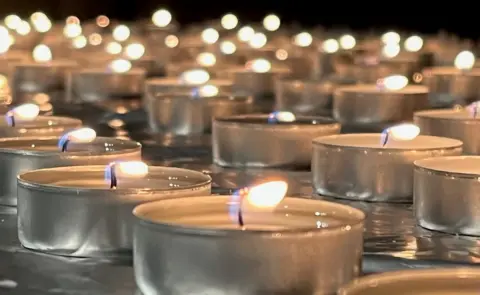 Kevin Shoesmith / BBC Candles lit at the vigil by some of the families affected