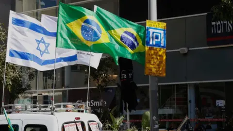 Getty Images The Israeli and Brazilian flags hanging outside the building housing the offices of the Brazilian Embassy in Tel Aviv