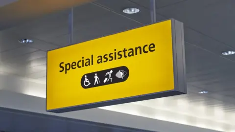 Heathrow Airports Limited A yellow illuminated sign with black symbols and the words 'special assistance'