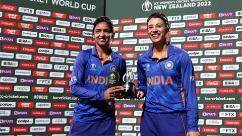 Getty Images Harmanpreet Kaur (L) and Smriti Mandhana of India pose with the Player of the Match Award during the 2022 ICC Women's Cricket World Cup match between West Indies and India at Seddon Park on March 12, 2022 in Hamilton, New Zealand