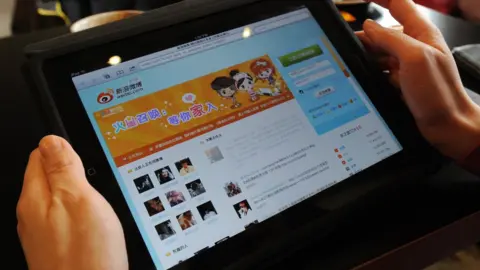 Getty Images A woman views the Chinese social media website Weibo at a cafe in Beijing