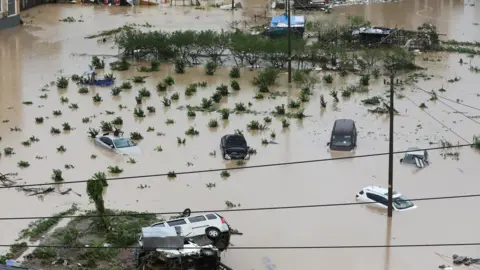Reuters Cars are partially submerged in flood water