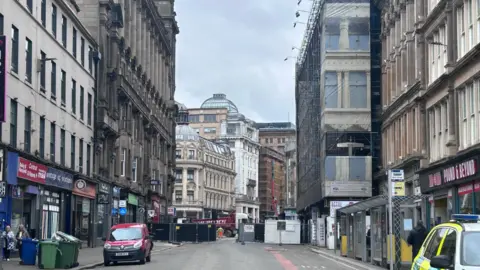Union Street cordon. The street is quiet. There is a van parked on the street and shops line both sides. 
