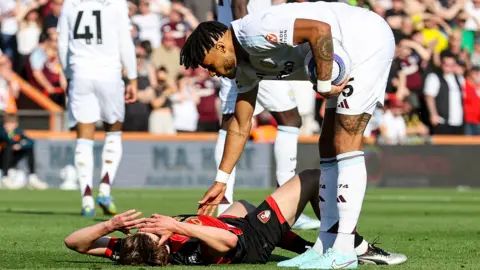 Tyron Mings checks on the injured Alex Scott