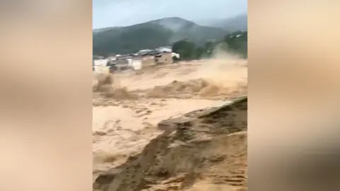 Muddy brown water flows after a reservoir break in China.