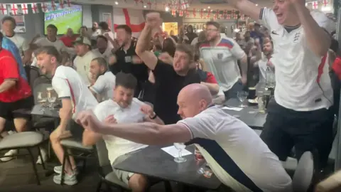 England fans celebrating a goal while watching the match at Bromsgrove Sporting