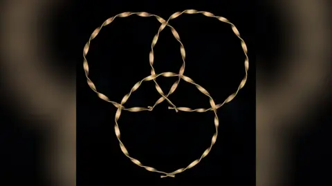 South Wales Police Gold bracelet-sized rings partially placed on top of one another, pictured against a black backdrop