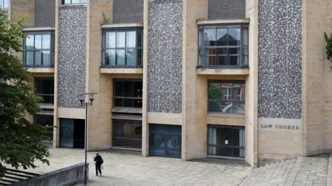 PA Media The Winchester Crown Court building, which has multiple doors at its entrance and windows on each level.The building is made of cream bricks but these are interspersed by stone walls.