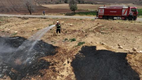 Firefighters work to put out a blaze near Diyabakir, Turkey, 21 June 