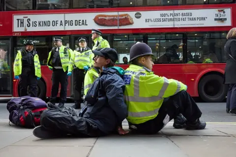 Thomas Bowles  A man sits back-to-back with a police officer