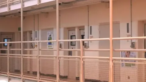 Ant Saddington/BBC A close up of one of the wings at HMP Woodhill. Posters have been stuck to some doors.