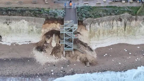 Eddie Mitchell A metal staircase on a cliff is surrounded with collapsed debris. 