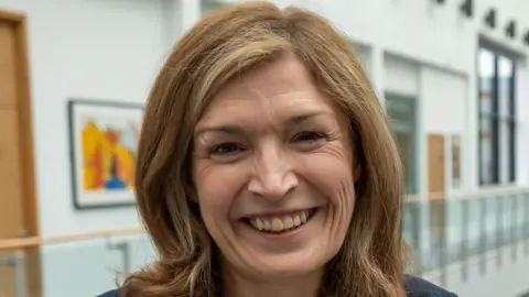 York St John University Dr Amanda Wilcox smiles and the camera. She has shoulder length brown hair.