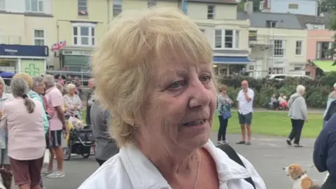 Dawlish resident Linda Stubbs looking unhappy. She is stood in front of a crowd of people.