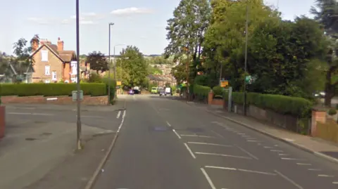Google Streetview The junction of a side road and more main road through a residential area. There is a yellow speed camera visible.