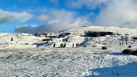 Lucy O | BBC Weather Watchers People sledge and walk in the snow on a hillside