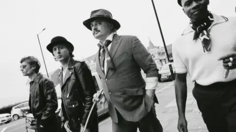 The Libertines are standing side by side in a black and white photo. 
