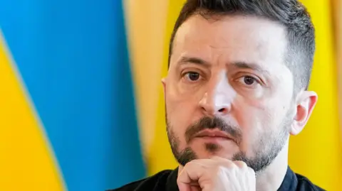 EPA Ukrainian President Volodymyr Zelensky holds his chin as he looks on during a Summit in London.