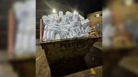 A skip filled with bottles of water. 