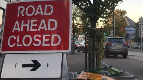 Red road closed sign in central Nelson with a yellow diversion sign on the floor.