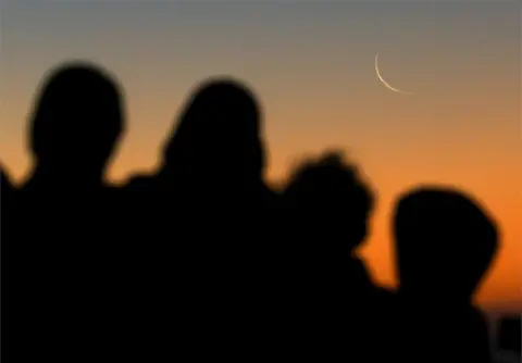 ESA ALEXANDER/REUTERS Muslims look at the crescent moon.