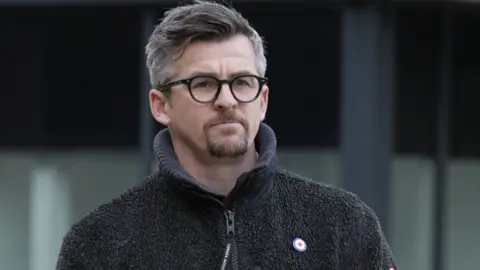 Joey Barton outside Liverpool Crown Court in a fleece and glasses. 