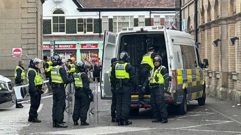 Humberside Police officers dressed in riot gear standing behind a police van